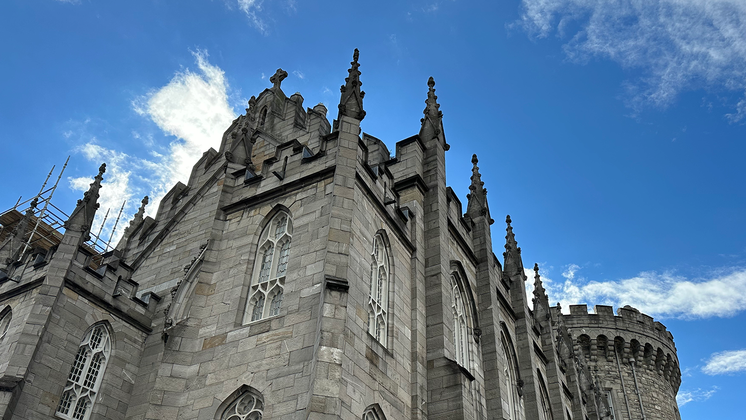 A photo looking up at the side of Dublin Castle. In the background, the sky is blue with wispy white clouds.